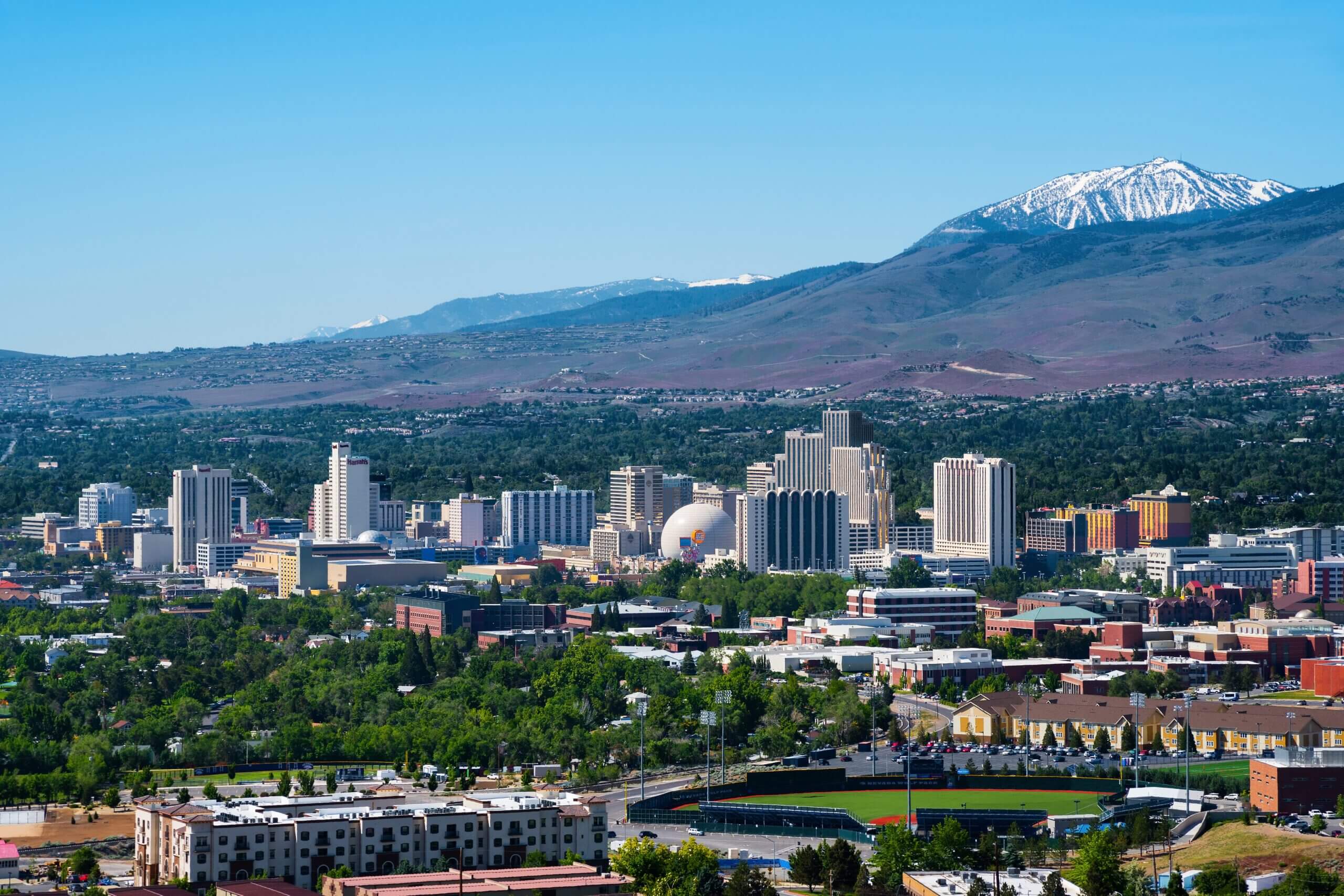 City skyline with mountains and a snow-capped peak in the background.