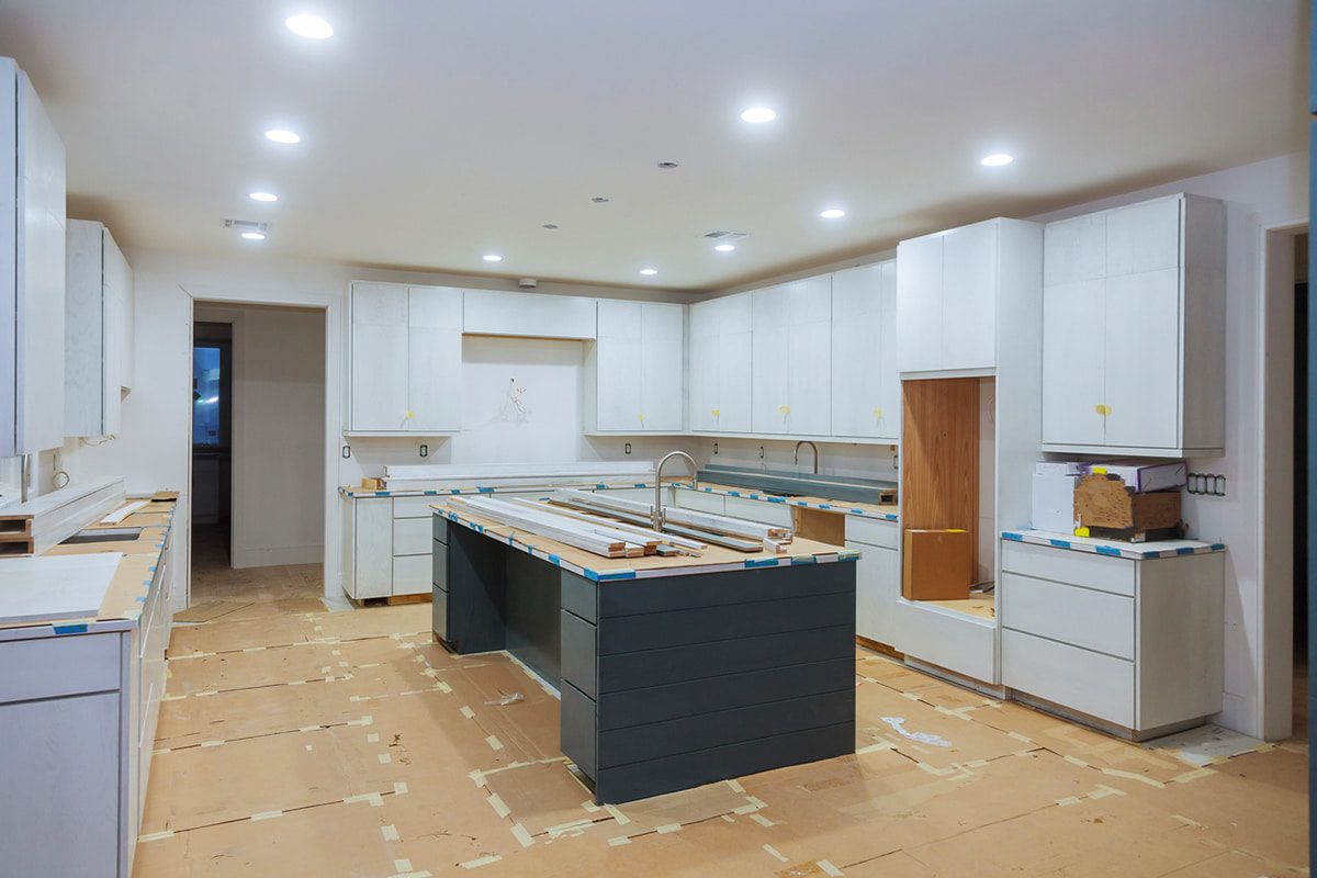 Modern kitchen under construction with a large island and white cabinets.