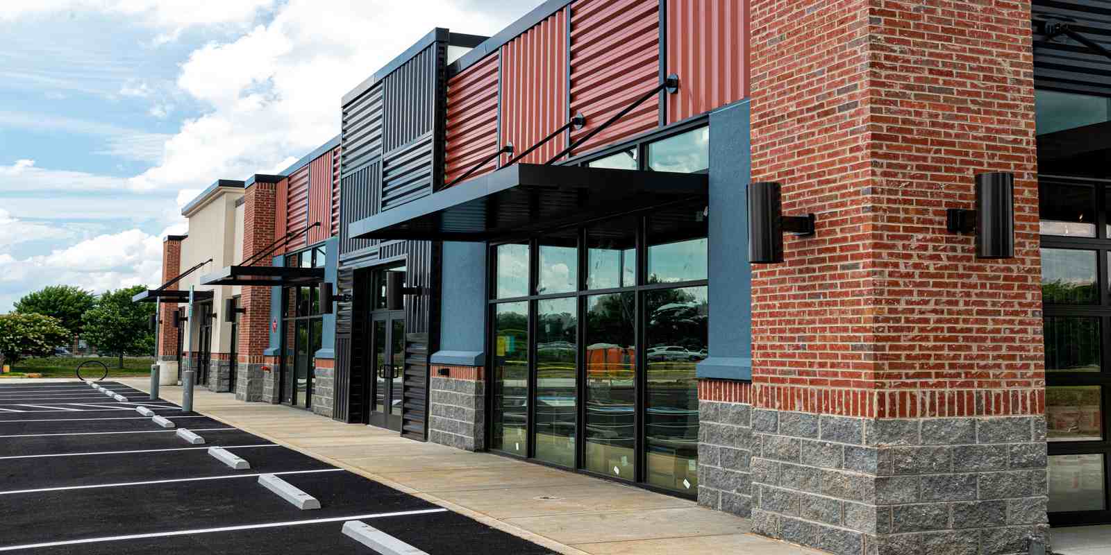 Modern commercial building entrance with glass doors and brick walls.